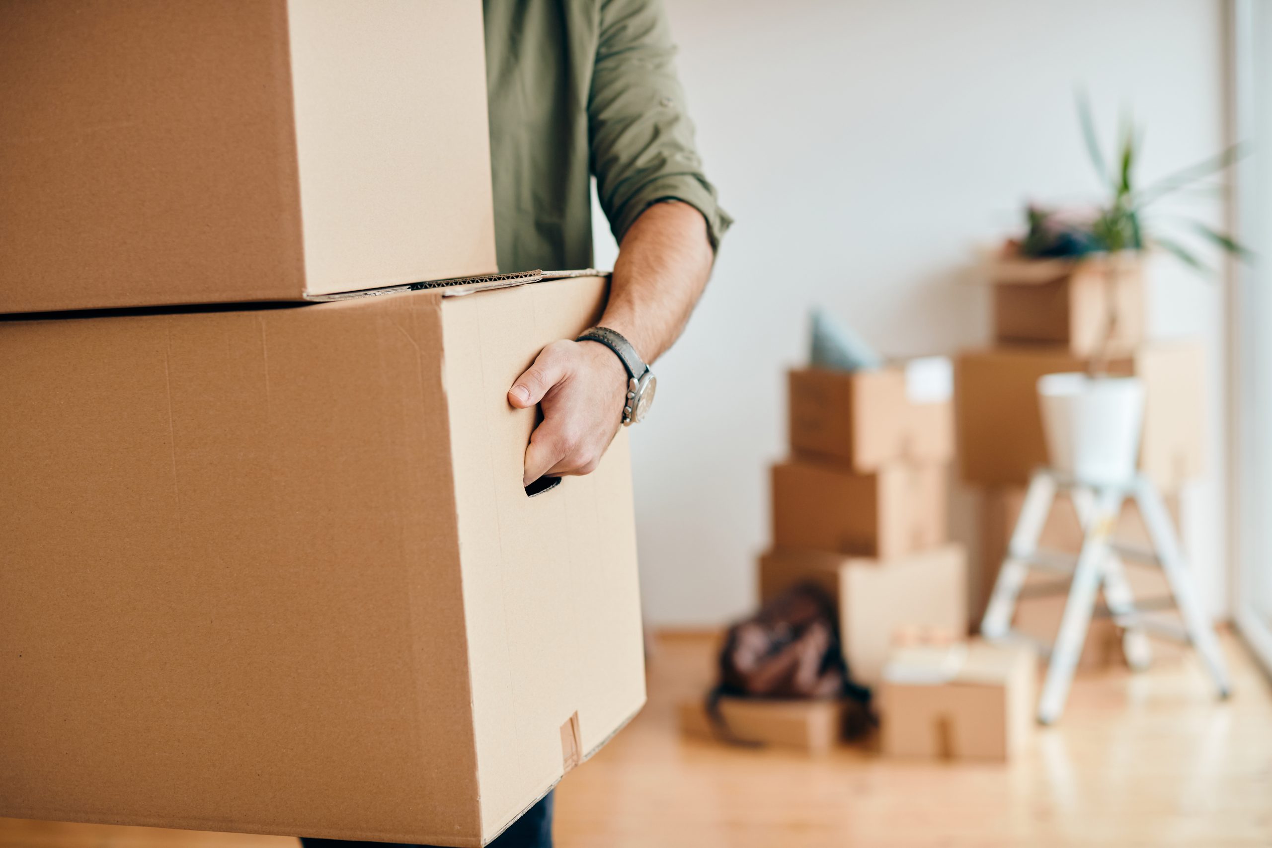 close up of man carrying cardboard boxes while relocating into n